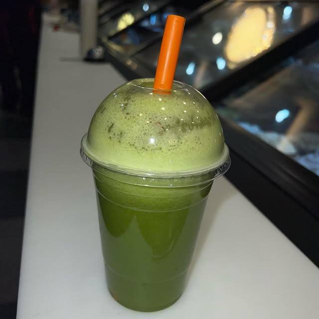 Fresh green juice in a cup with a straw